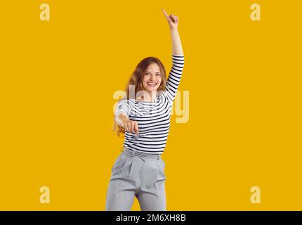 Portrait de bonne drôle jeune fille dansant et sautant isolé sur fond jaune Banque D'Images