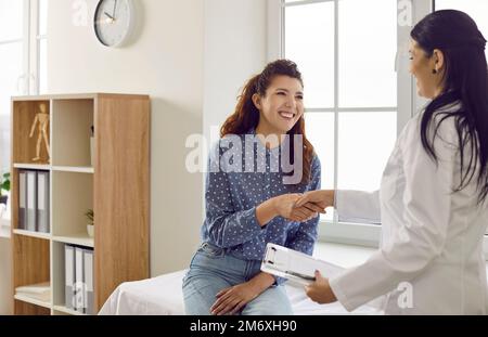 Une patiente heureuse et reconnaissante tremble les mains avec son médecin après une réunion de consultation dans le bureau de l'hôpital. Banque D'Images