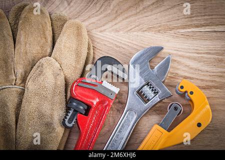 Composition de gants de sécurité clé à molette monkey clé coupe-tube sur bois concept de plomberie. Banque D'Images