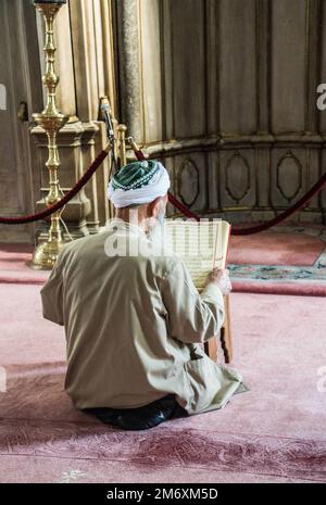 Un vieil homme qui lit Quran dans une mosquée Banque D'Images