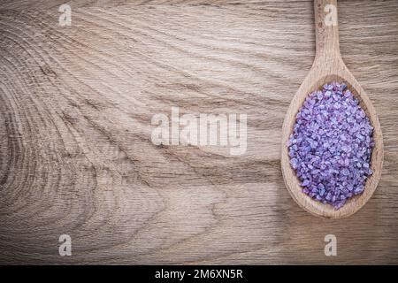 Sel de mer violet lavande en cuillère en bois sur planche à bois concept de soin spa. Banque D'Images