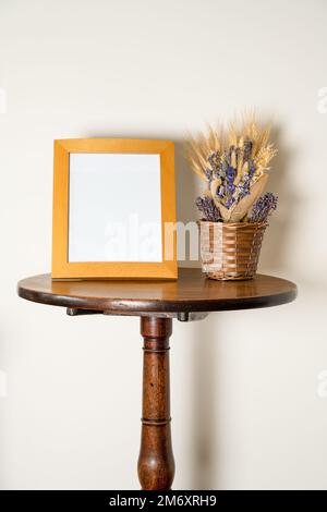 table sur pied intérieure mockup lifestyle avec cadre photo vide et panier de fleurs séchées Banque D'Images