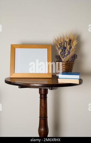 table sur pied intérieure mockup style de vie avec cadre photo vide panier de fleurs séchées et de livres Banque D'Images