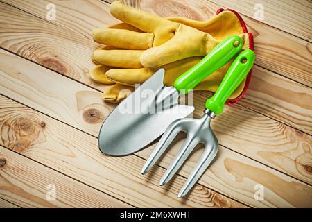 fourche à main et fourche de jardin avec gants en cuir jaune sur bois Banque D'Images