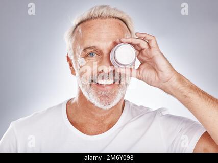 Portrait, homme senior et crème pour les soins de la peau, la beauté et les cosmétiques sur fond gris studio. Visage, homme mature et homme âgé avec lotion, sérum et Banque D'Images