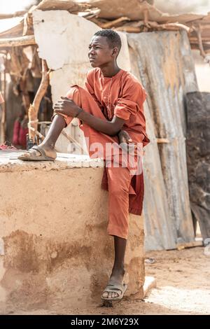 Un jeune garçon regarde une discussion entre le Groupe expéditionnaire aérien 409th (AEG) et les forces armées nigériennes (langue française: Forces armées nigériennes - FAN), les équipes des affaires civiles et le chef de village et chef adjoint à Alwat, Niger, 9 mai 2022. Ces réunions, facilitées par l'équipe des affaires civiles de l'AEG en 409th, renforcent le partenariat du FAN avec les villages locaux, ce qui permet d'établir de solides relations et de renforcer la continuité de l'engagement entre le gouvernement du Niger et ses citoyens. Banque D'Images