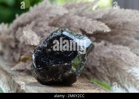 Échantillon de roche minérale obsidienne noire sur fond en bois. Formes de verre volcanique naturel de Lava Banque D'Images
