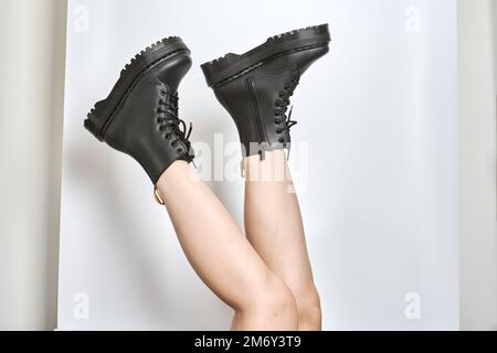 Femme jambes dans des bottes de combat noires sur la plate-forme à talon haut avec des semelles de patte à l'envers vue latérale sur un arrière-plan blanc isolé. Les jambes des femmes portent un fa militaire Banque D'Images