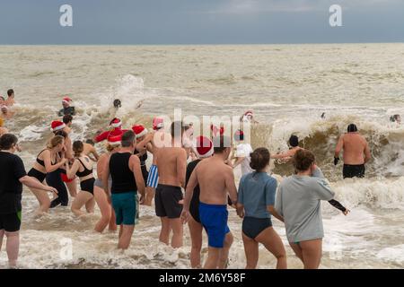 Des centaines de nageurs s'embattent dans une mer agitée le jour de Noël sur la plage de Brighton dans le cadre des festivités avec un plongeon revigorant. Brighton, Banque D'Images