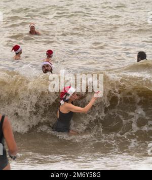 Des centaines de nageurs s'embattent dans une mer agitée le jour de Noël sur la plage de Brighton dans le cadre des festivités avec un plongeon revigorant. Brighton, Banque D'Images