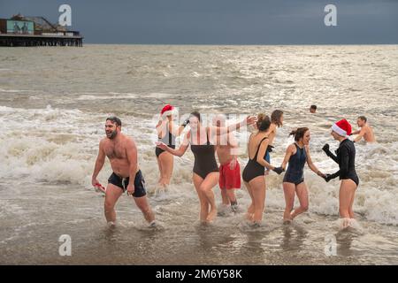 Des centaines de nageurs s'embattent dans une mer agitée le jour de Noël sur la plage de Brighton dans le cadre des festivités avec un plongeon revigorant. Brighton, Banque D'Images