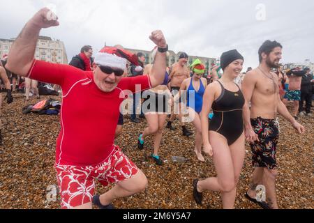 Des centaines de nageurs s'embattent dans une mer agitée le jour de Noël sur la plage de Brighton dans le cadre des festivités avec un plongeon revigorant. Brighton, Banque D'Images