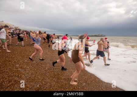 Des centaines de nageurs s'embattent dans une mer agitée le jour de Noël sur la plage de Brighton dans le cadre des festivités avec un plongeon revigorant. Brighton, Banque D'Images