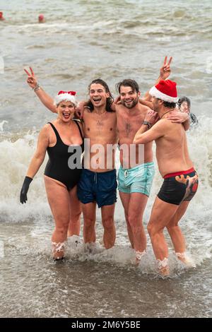 Des centaines de nageurs s'embattent dans une mer agitée le jour de Noël sur la plage de Brighton dans le cadre des festivités avec un plongeon revigorant. Brighton, Banque D'Images