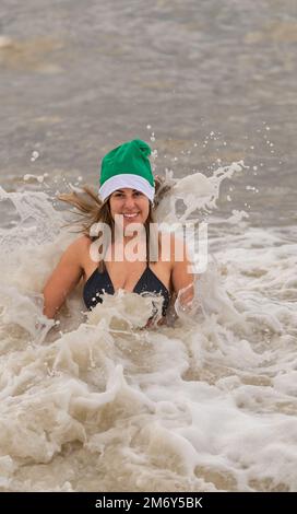 Des centaines de nageurs s'embattent dans une mer agitée le jour de Noël sur la plage de Brighton dans le cadre des festivités avec un plongeon revigorant. Brighton, Banque D'Images