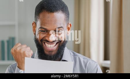 Succès ethnique gagnant homme excité homme exécutif lecture mail salaire croissance offre d'emploi se sentir choc surprise approbation de prêt d'affaires. Bonne ethnie africaine Banque D'Images