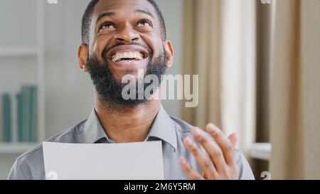 Heureux gagnant ethnique employé de bureau homme d'affaires africain homme d'affaires ethnique barbu américain gestionnaire entrepreneur homme lecture courrier avec invitation Banque D'Images