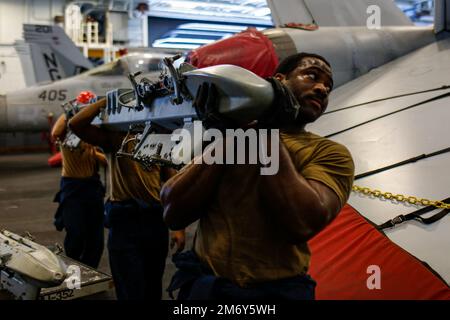 LES marins DE LA MER DES PHILIPPINES (10 mai 2022) déplacent du matériel d'ordnance dans la baie hangar à bord du porte-avions de la classe Nimitz USS Abraham Lincoln (CVN 72). Abraham Lincoln Strike Group est en cours de déploiement prévu dans la zone d'exploitation de la flotte américaine 7th afin d'améliorer l'interopérabilité par le biais d'alliances et de partenariats tout en servant de force de réaction prête à l'emploi pour soutenir une région libre et ouverte d'Indo-Pacifique. Banque D'Images