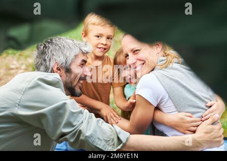 Des parents heureux embrassant leur fille et leur fils en campant ensemble en forêt Banque D'Images