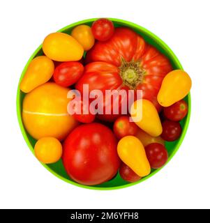 Différents types de tomates biologiques dans un bol isolé sur fond blanc Banque D'Images