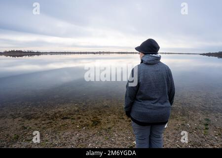 Femme solitaire debout près d'un appartement de marée en hiver Banque D'Images