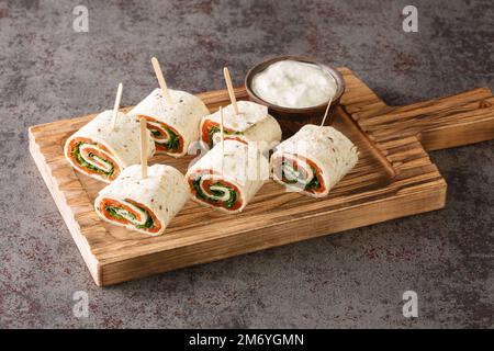 De savoureux petits pains avec du saumon, du fromage et des légumes pour un brunch en gros plan sur le plateau de la table. Horizontale Banque D'Images