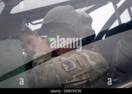 Un soldat affecté à 1-229th Attack BN., 16th combat Aviation Brigade ajuste son casque et se prépare à monter dans un hélicoptère AH-64E Apache à la base interarmées Lewis-McChord, Washington, le 20 avril 2022. L'Apache n'a pas de membres d'équipage inscrits qui accompagnent l'avion pendant le vol, ce qui fait de cette récompense pour les soldats de haute performance un événement spécial et peu fréquent. Banque D'Images