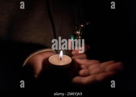 Fille tient une ampoule électrique et une bougie allumée dans ses mains. Panne. Destruction des infrastructures. Crise énergétique. Concept de coupure de courant Banque D'Images