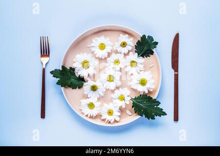 Assiette à fleurs blanches, fourchette et couteau. Concept de régime. Vue de dessus, plan d'agencement. Banque D'Images