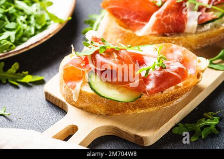 Sandwichs ouverts avec fromage à la crème, prosciutto, concombre et arugula. Banque D'Images