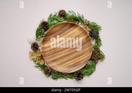 Modèle de carte de Noël et du nouvel an sur plaque en bois avec fleurs séchées, branches de thuya, bourgeons de thuya et cônes de sapin, plat, vue du dessus Banque D'Images