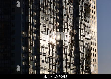 Silhouette de nouveau bâtiment résidentiel, le soleil se reflète dans les balcons vitrés avec des paniers pour climatiseurs. Développement de la maison Banque D'Images