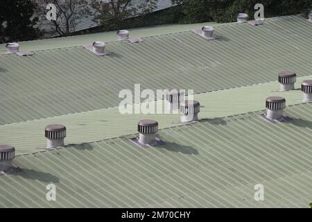 Les ventilateurs d'air qui ne sont pas entraînés par l'énergie sur le toit de certaines petites industries. Des ventilateurs sur le toit qui tournent et prennent le vent dans le bâtiment Banque D'Images