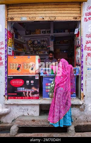 Pushkar, Inde - 7 novembre 2019: Magasin électronique de rue vendeur en haut recharge femme téléphone mobile dans la rue de Pushkar, Rajasthan, Inde Banque D'Images