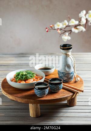 Saké japonais et saumon sashimi et algues wakame sur table en bois asiatique Banque D'Images