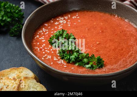 Gazpacho garni de persil dans une assiette à bords ondulés. Banque D'Images