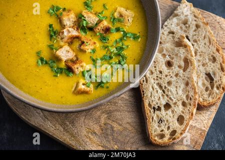Soupe à la crème de courgettes. Le plat est sur une planche à découper avec deux morceaux de pain. Vue de dessus. Banque D'Images