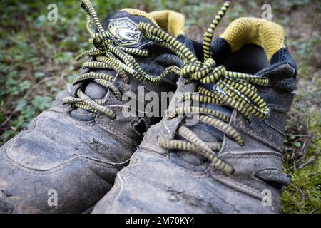 Les vieilles chaussures de travail de sécurité sont usées par les travaux difficiles dans les champs. Banque D'Images