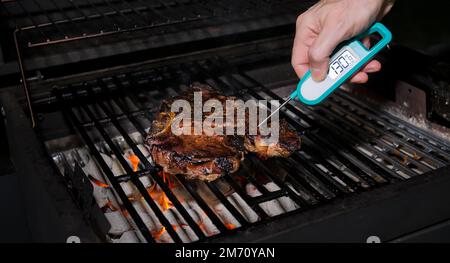 Contrôle de la température des aliments avec un thermomètre instantané numérique. Faire cuire en mesurant la température du steak fraîchement grillé sur le barbecue chaud. Banque D'Images
