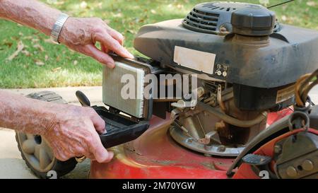 Homme paysagiste remplaçant le filtre à air sur une tondeuse à gaz. Vérification de l'entretien correct du filtre à air. Banque D'Images
