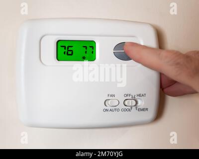 Gros plan sur un réglage de la température de la pièce à l'aide d'un thermostat d'ambiance programmable. Banque D'Images