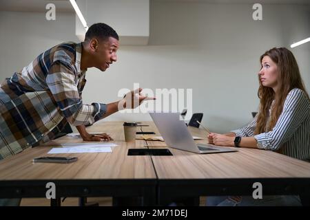 Un homme insatisfait se disputant avec sa collègue dans la salle de réunion Banque D'Images