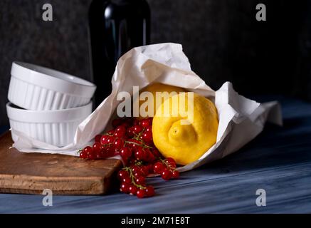 Citrons et raisins de Corinthe fraîchement achetés dans un sac en papier et des plats à gratin blancs Banque D'Images