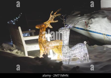 Décorations électriques dans une rue enneigée d'hiver, éclairage de nuit, Noël en Europe, avec lampes à rennes faites d'ampoules et de fil Banque D'Images