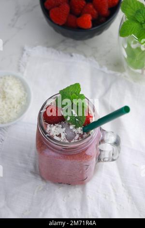 smoothie à la noix de coco et à la framboise avec glace dans un pot à la paille, fond blanc Banque D'Images