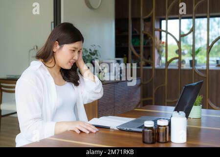 Inquiète jeune femme enceinte tenant la main sur sa tête et communiquant avec le médecin sur le Web. Télémédecine, grossesse, bébé attendu et soins de santé Banque D'Images