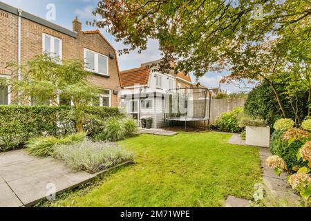 une maison dans la banlieue, avec de l'herbe verte et des buissons de chaque côté à l'avant de la maison il y a un petit jardin Banque D'Images