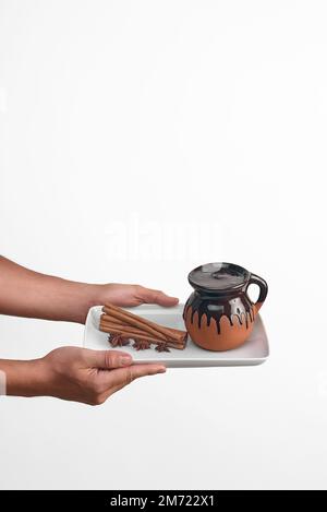 un homme tenant une assiette blanche avec du champurrado au chocolat, de l'anis et de la cannelle, une boisson traditionnelle mexicaine au chocolat sur fond blanc, des objets Banque D'Images