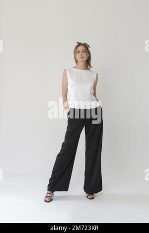 Série de photos de studio de jeune femme modèle en soie noire et blanche tenue, chemisier sans manches et pantalon à jambes larges Banque D'Images