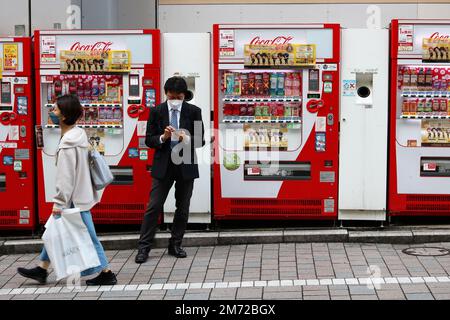 TOKYO, JAPON - 24 novembre 2022: Une ligne de distributeurs de boissons dont un avec la décoration Coca Cola dans une rue de la région de Shijuku à Tokyo. Banque D'Images